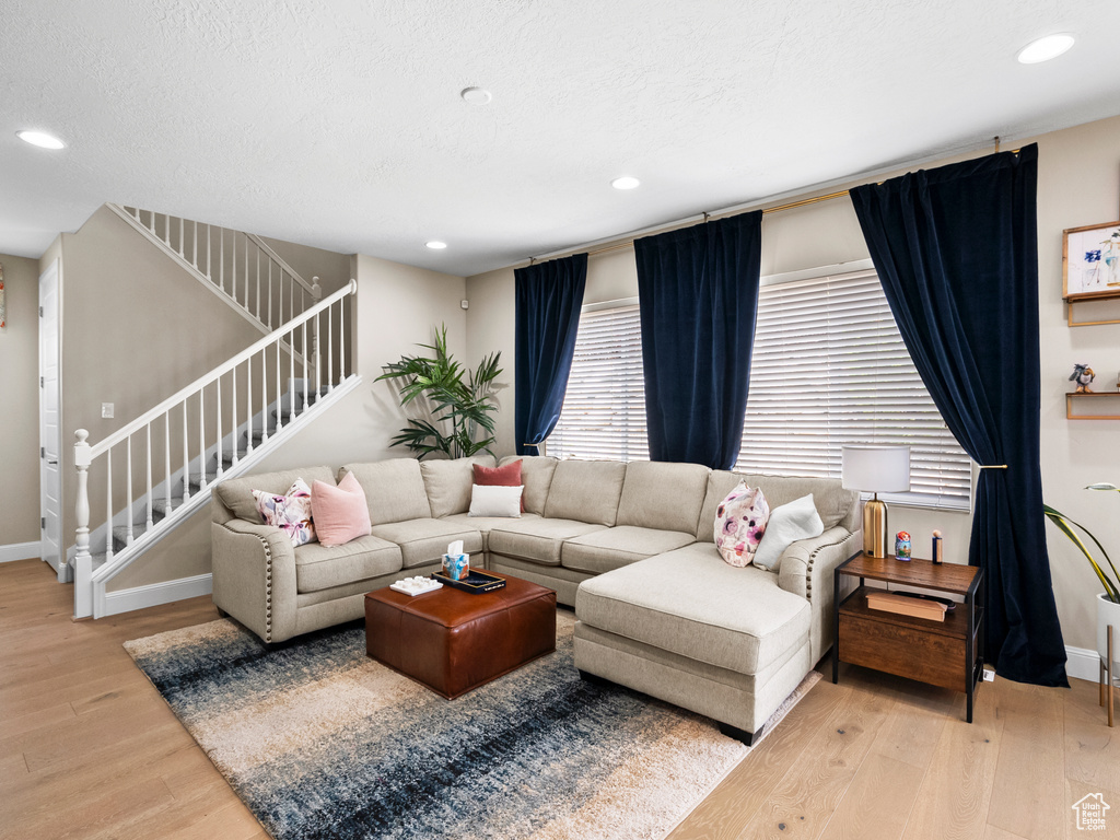Living area featuring stairway, light wood finished floors, recessed lighting, and a textured ceiling