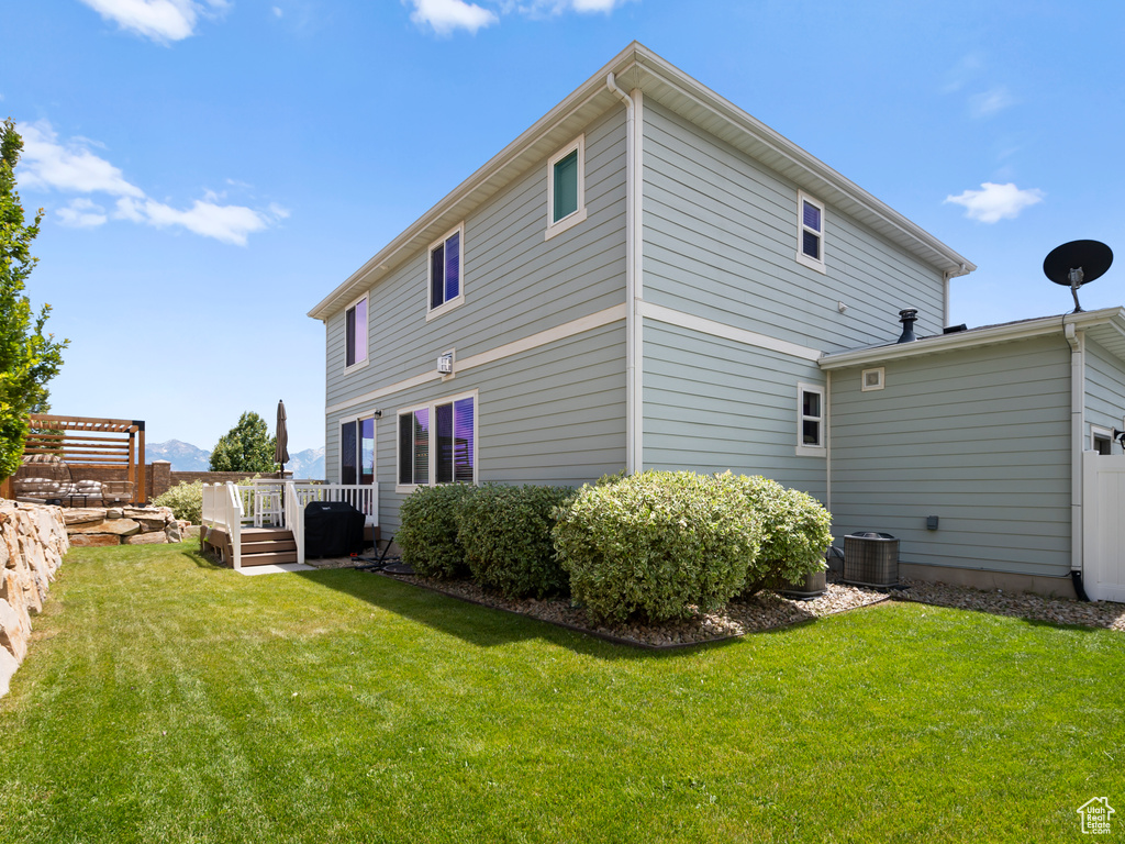 Back of house with a lawn and a deck