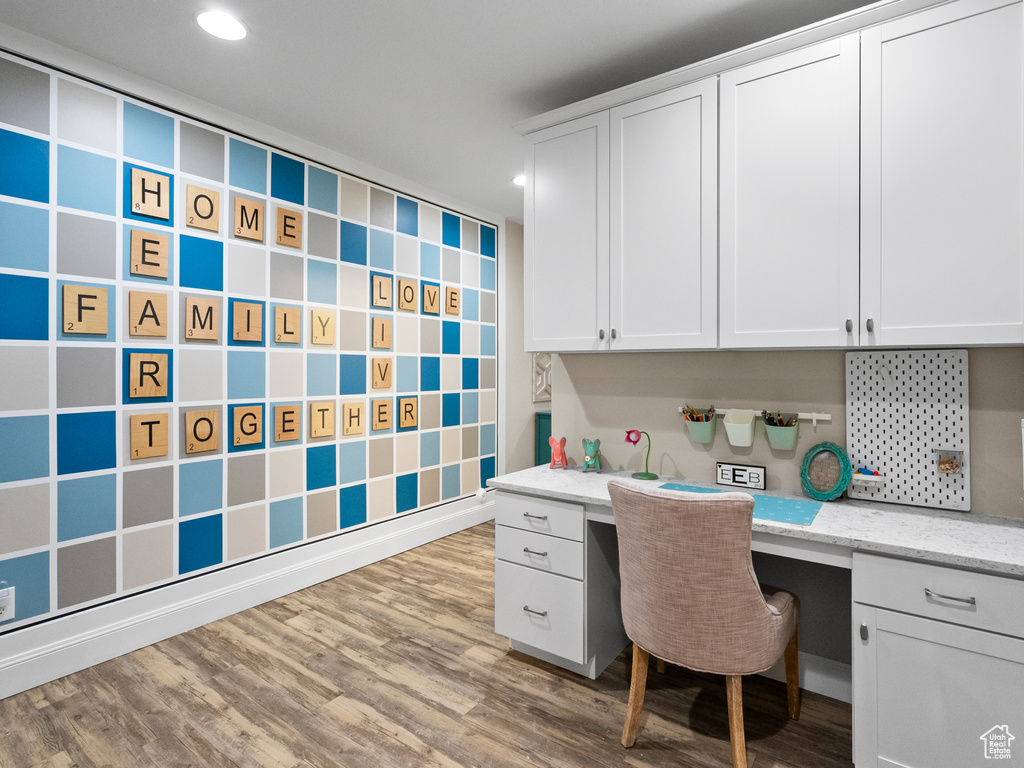 Home office with built in desk, wood finished floors, and recessed lighting