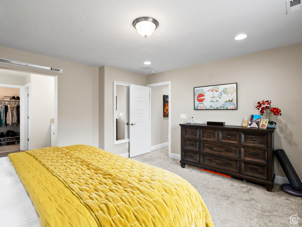 Bedroom featuring light colored carpet, a spacious closet, recessed lighting, and a closet