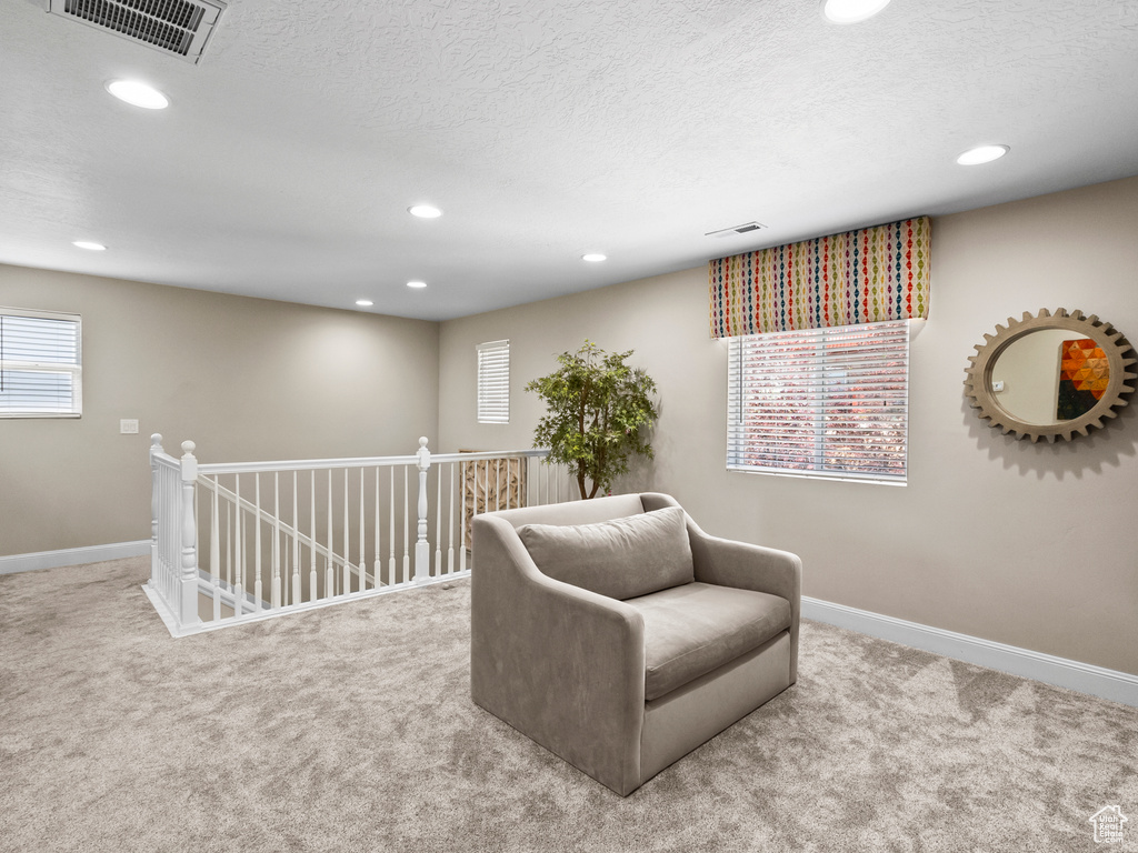 Living area featuring carpet floors, recessed lighting, healthy amount of natural light, an upstairs landing, and a textured ceiling