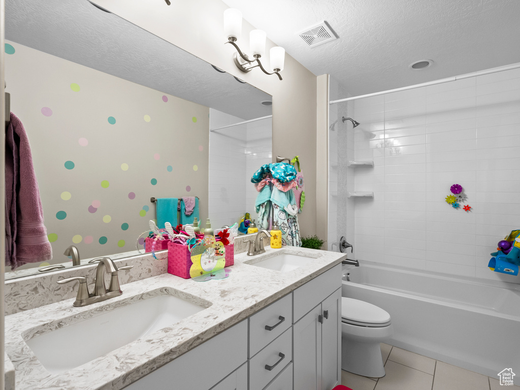 Full bathroom featuring double vanity, a textured ceiling, tile patterned floors, and  shower combination