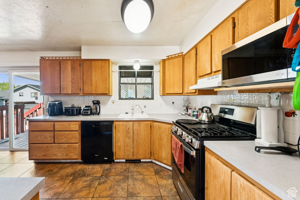 Kitchen featuring appliances with stainless steel finishes, plenty of natural light, under cabinet range hood, and decorative backsplash