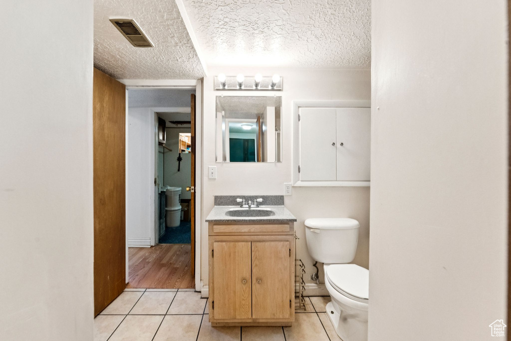 Half bathroom with tile patterned floors, vanity, and a textured ceiling