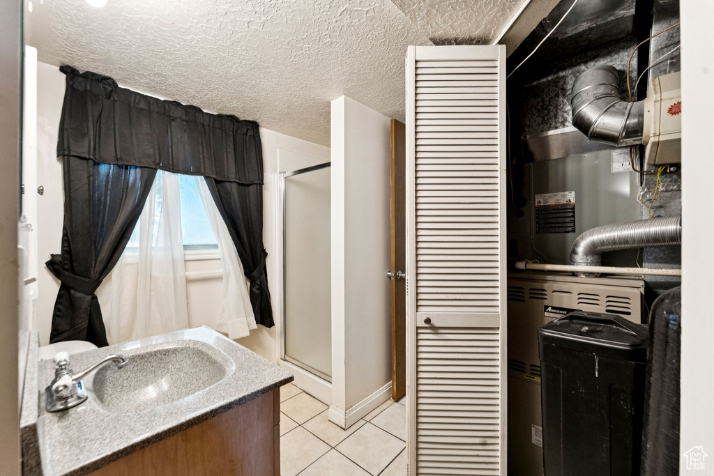 Bathroom featuring tile patterned flooring, a shower stall, vanity, and a textured ceiling
