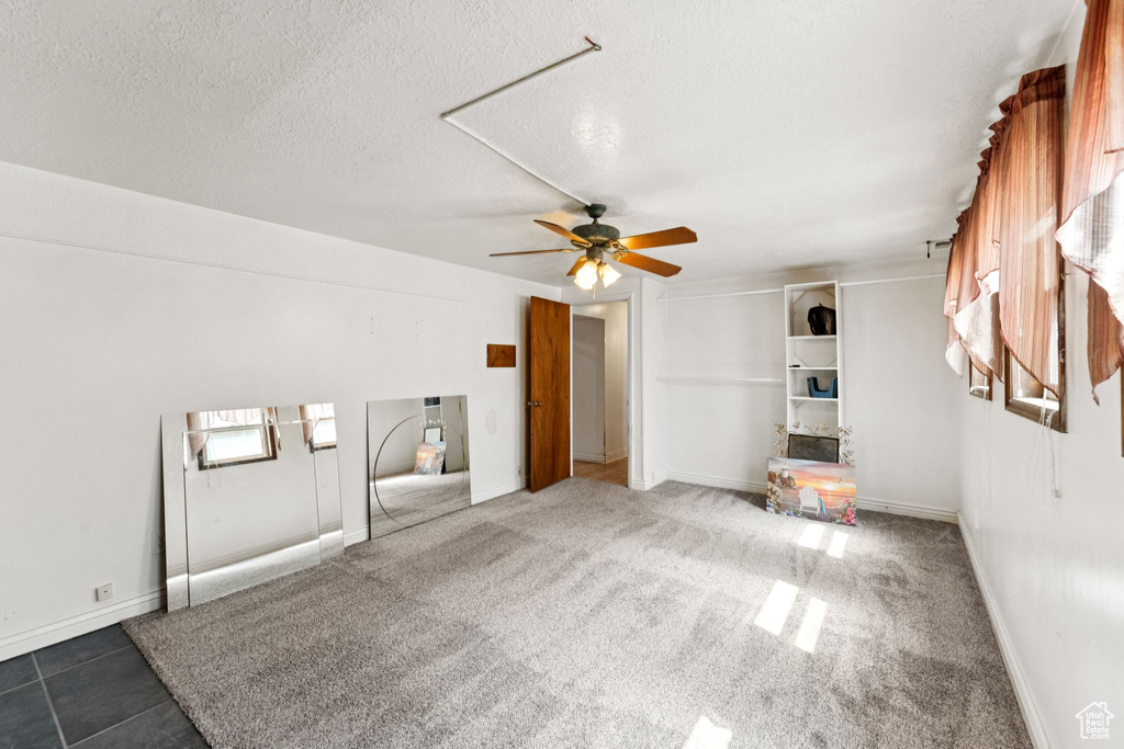 Unfurnished living room featuring ceiling fan and a textured ceiling