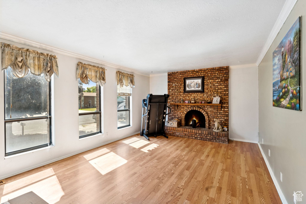 Unfurnished living room featuring crown molding, wood finished floors, and a fireplace