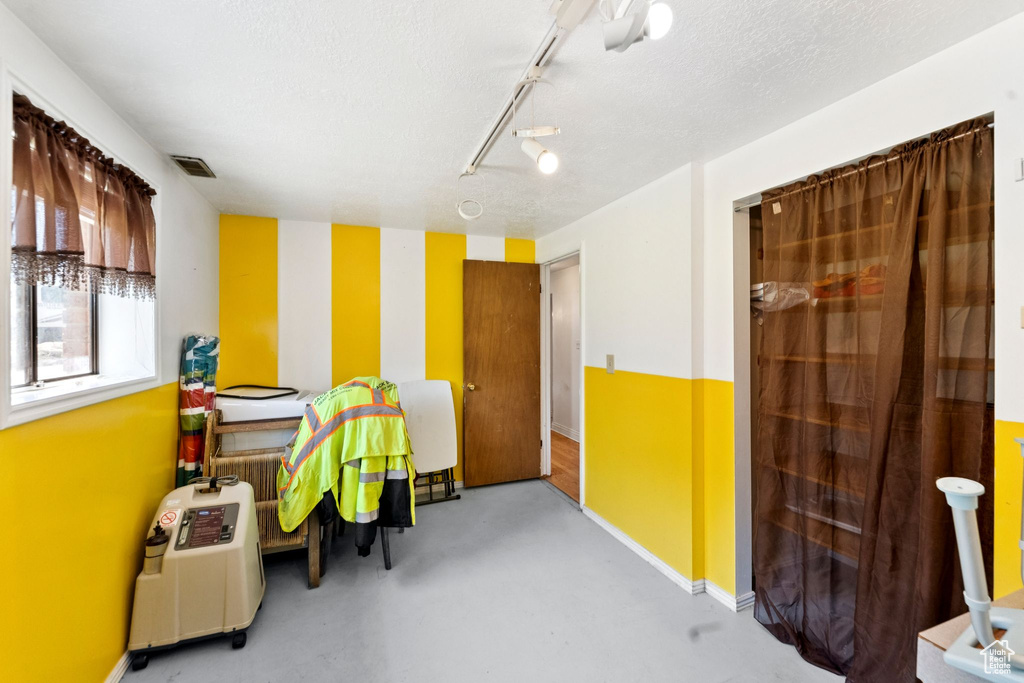 Office featuring finished concrete flooring, rail lighting, and a textured ceiling