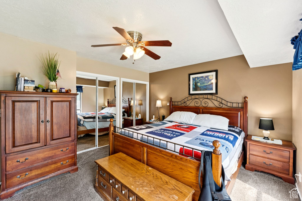 Bedroom featuring dark colored carpet, multiple closets, and ceiling fan