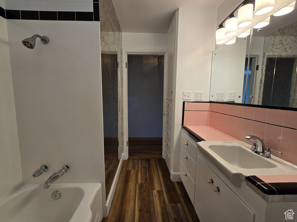 Bathroom featuring wood finished floors, vanity, a bath, backsplash, and a shower