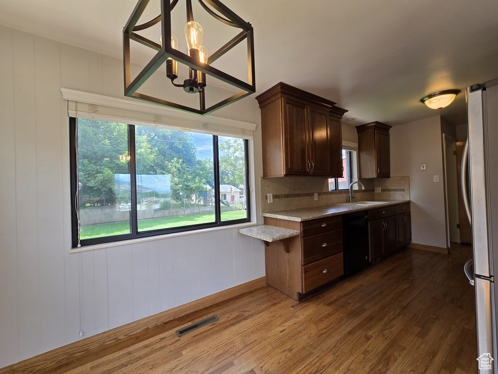 Kitchen with dishwasher, wood finished floors, freestanding refrigerator, and plenty of natural light