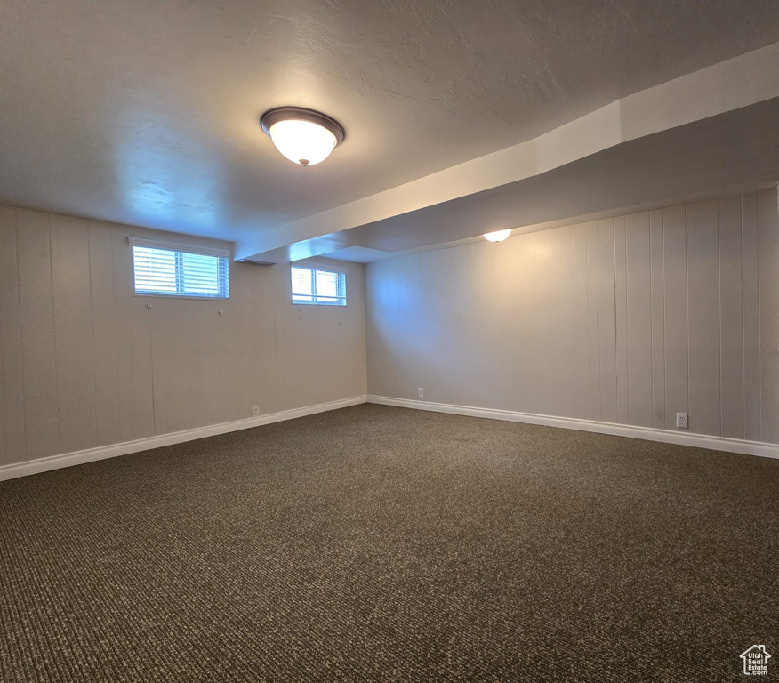 Basement featuring dark carpet and baseboards