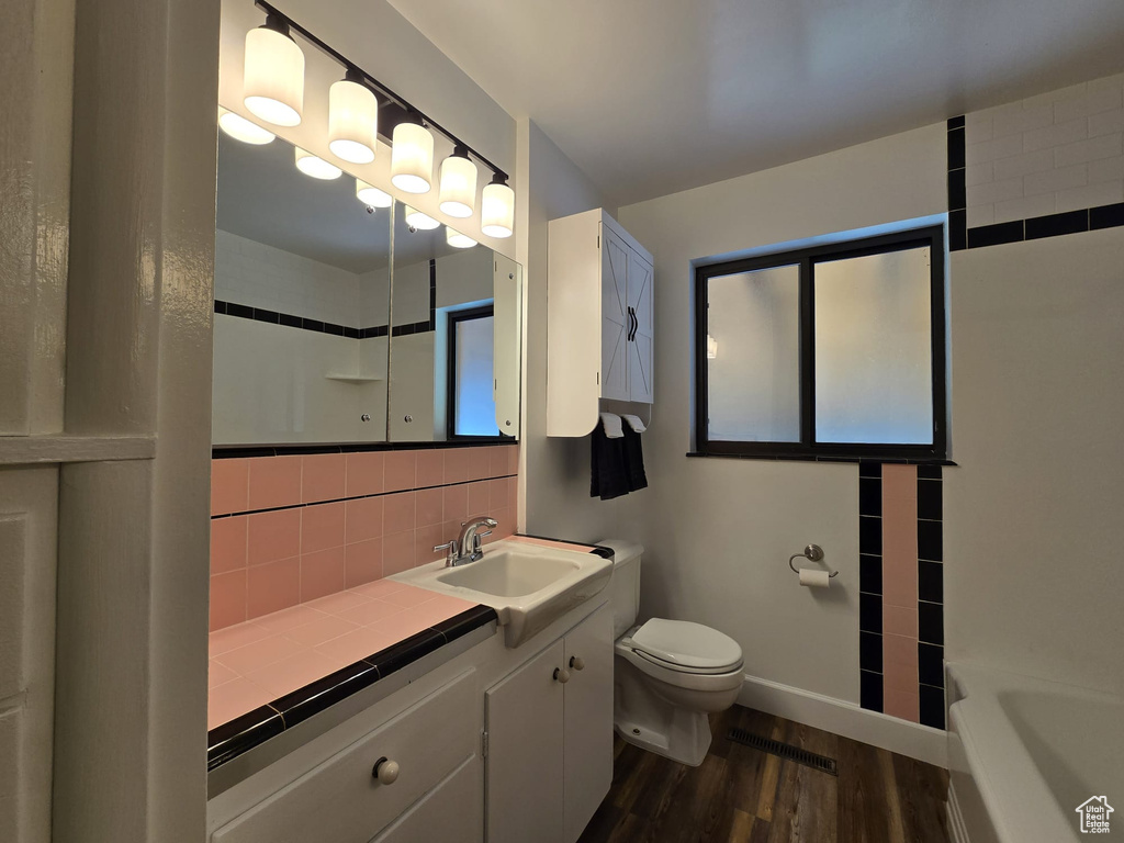 Full bath featuring wood finished floors, vanity, backsplash, a shower, and a tub