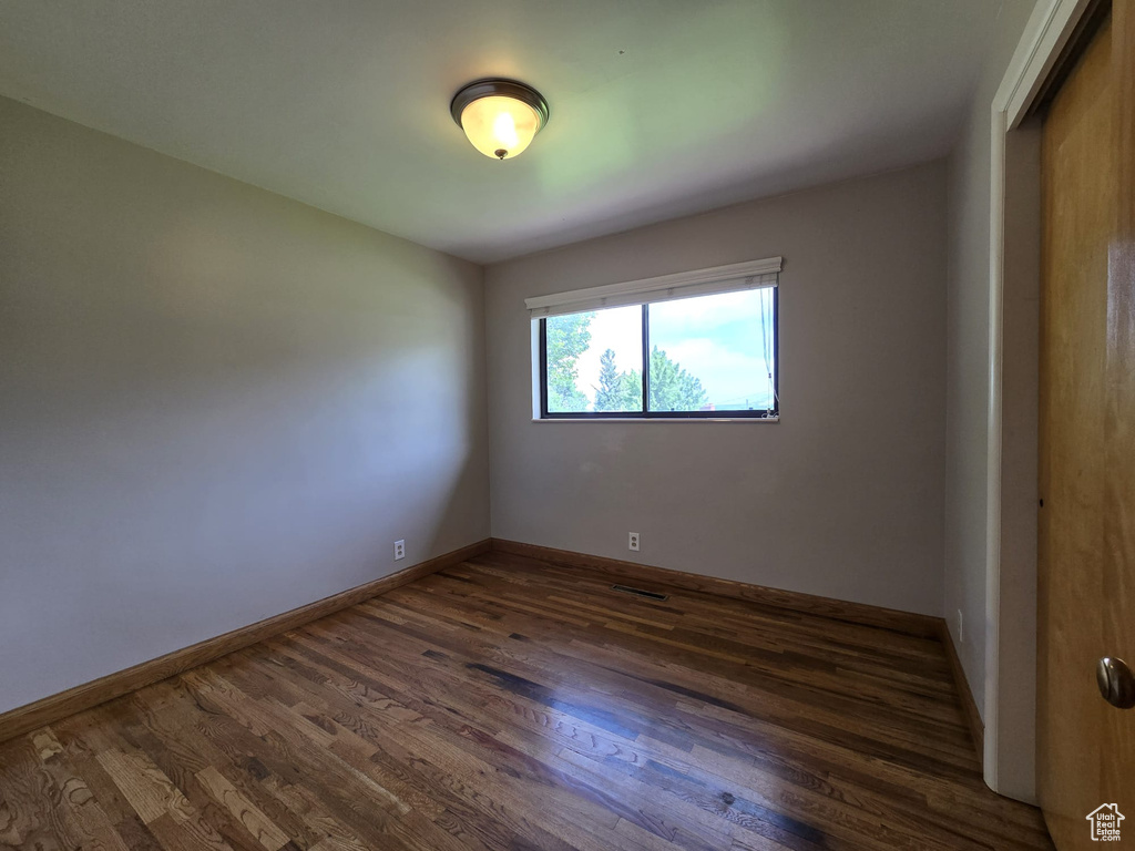 Unfurnished room with dark wood-style floors and baseboards