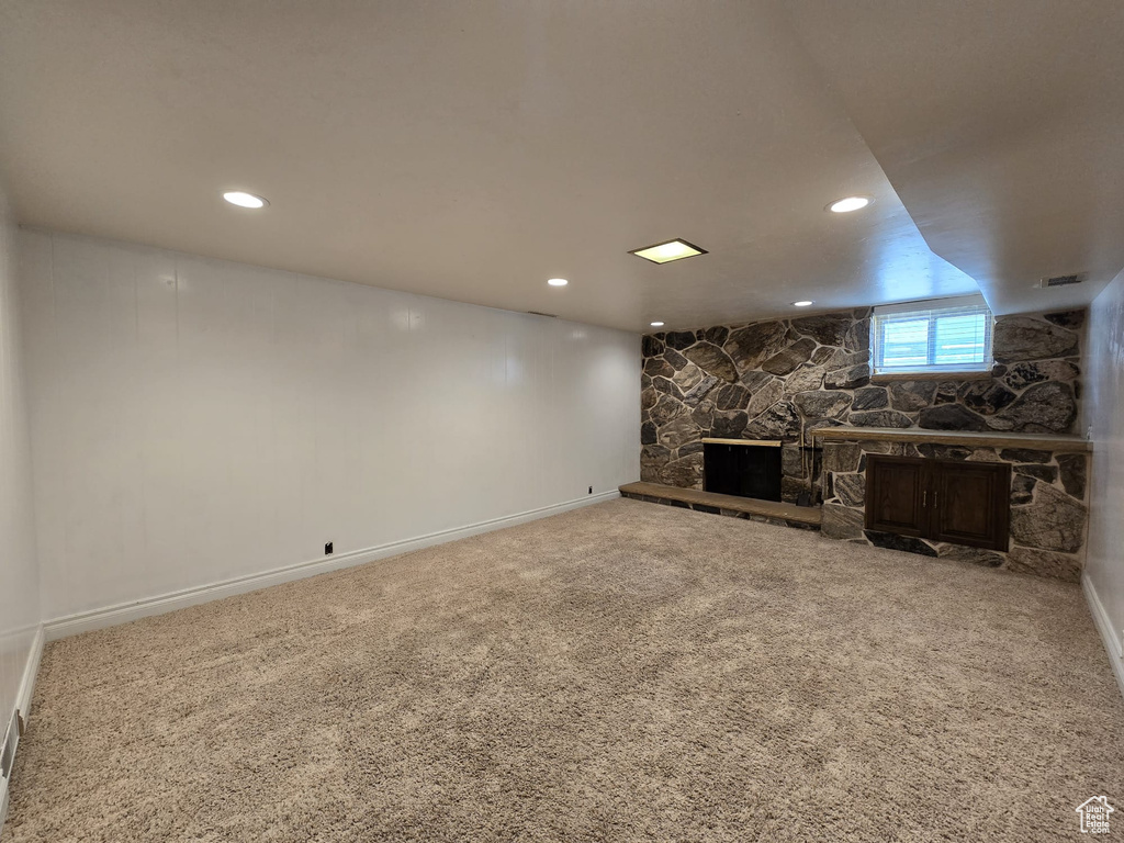 Unfurnished living room featuring a stone fireplace, carpet, and recessed lighting