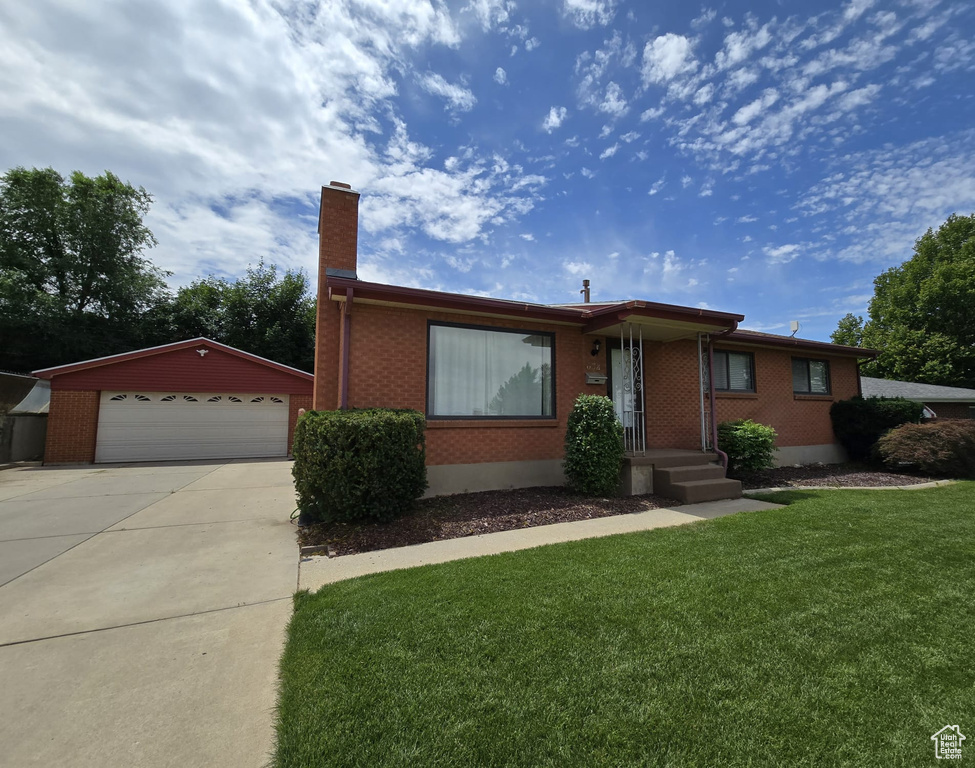 Ranch-style home with a chimney, brick siding, an outbuilding, a garage, and a front lawn