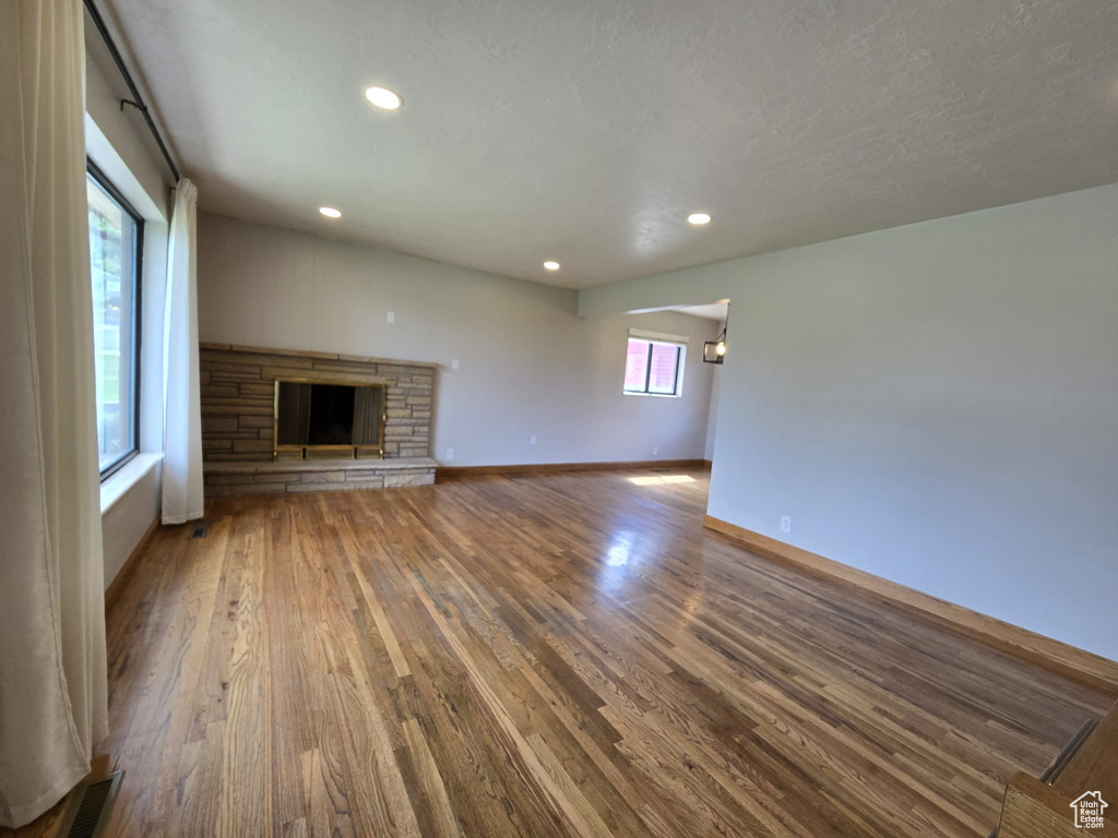 Unfurnished living room featuring a stone fireplace, wood finished floors, and recessed lighting