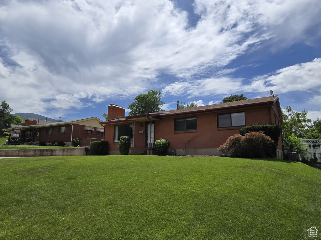 View of front of home featuring brick siding, a front yard, and a chimney