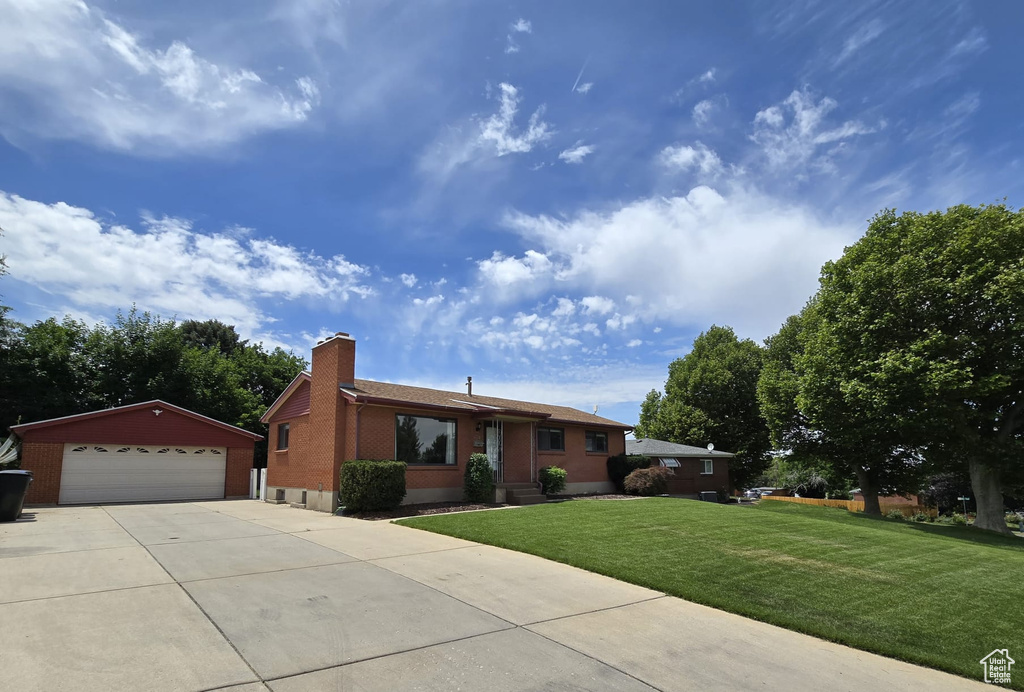 Ranch-style house with an outbuilding, a front yard, a chimney, a garage, and brick siding
