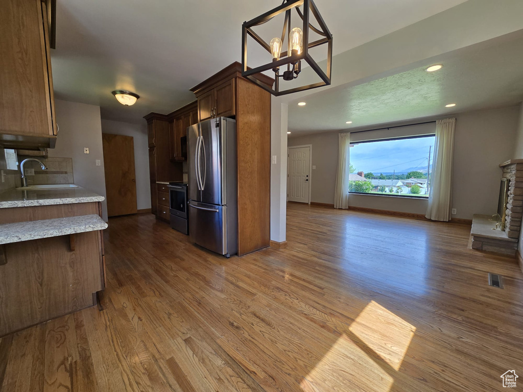 Kitchen featuring stainless steel appliances, dark wood-style flooring, a chandelier, open floor plan, and light stone counters
