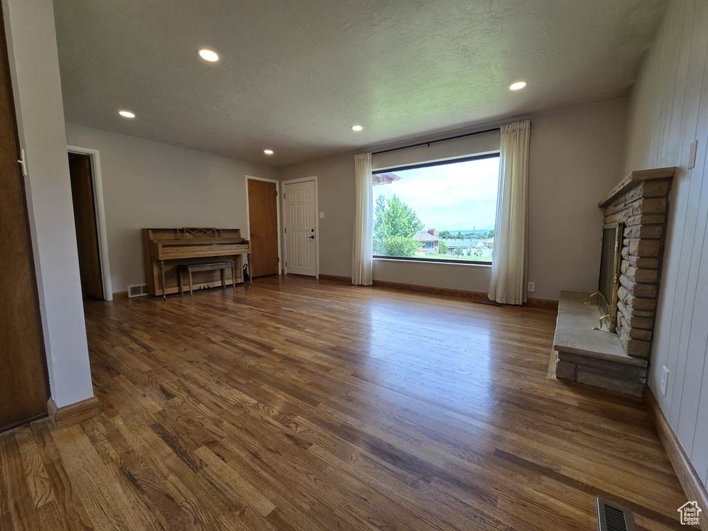 Unfurnished living room featuring recessed lighting, wood finished floors, and a fireplace
