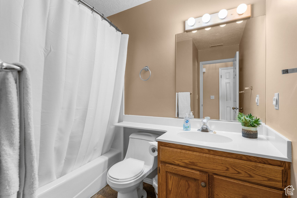 Full bath with vanity, a textured ceiling, and shower / bath combo