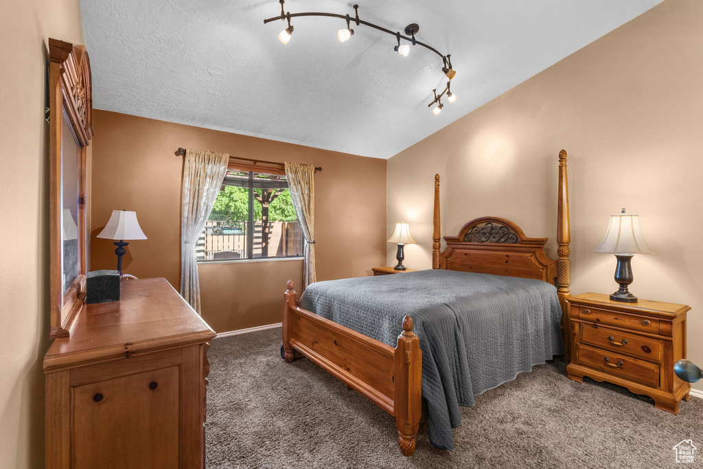 Bedroom with carpet floors, vaulted ceiling, and a textured ceiling