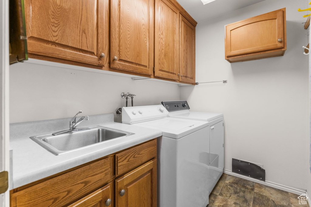 Laundry area with cabinet space, independent washer and dryer, and dark stone finish flooring