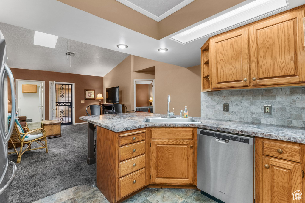 Kitchen featuring appliances with stainless steel finishes, a peninsula, tasteful backsplash, ornamental molding, and open floor plan