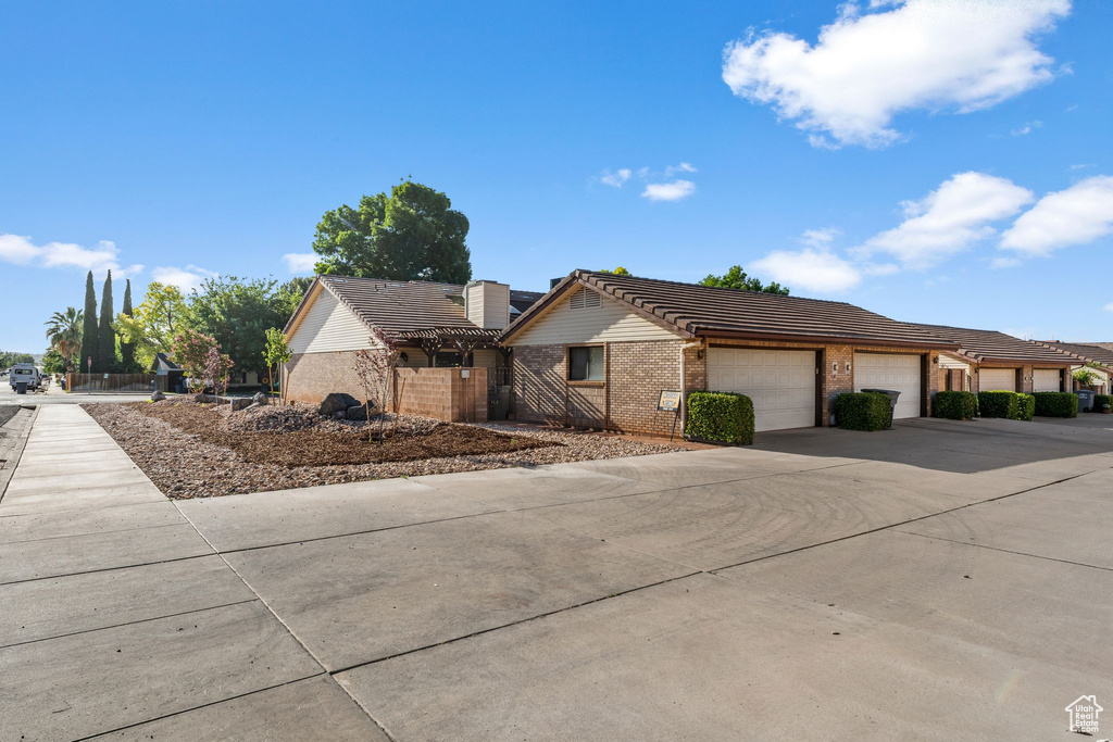 View of front of home with brick siding, driveway, a tiled roof, and an attached garage