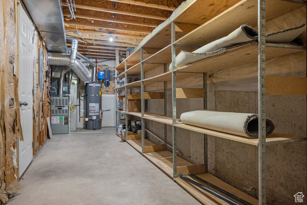 Unfinished below grade area featuring strapped water heater and heating unit