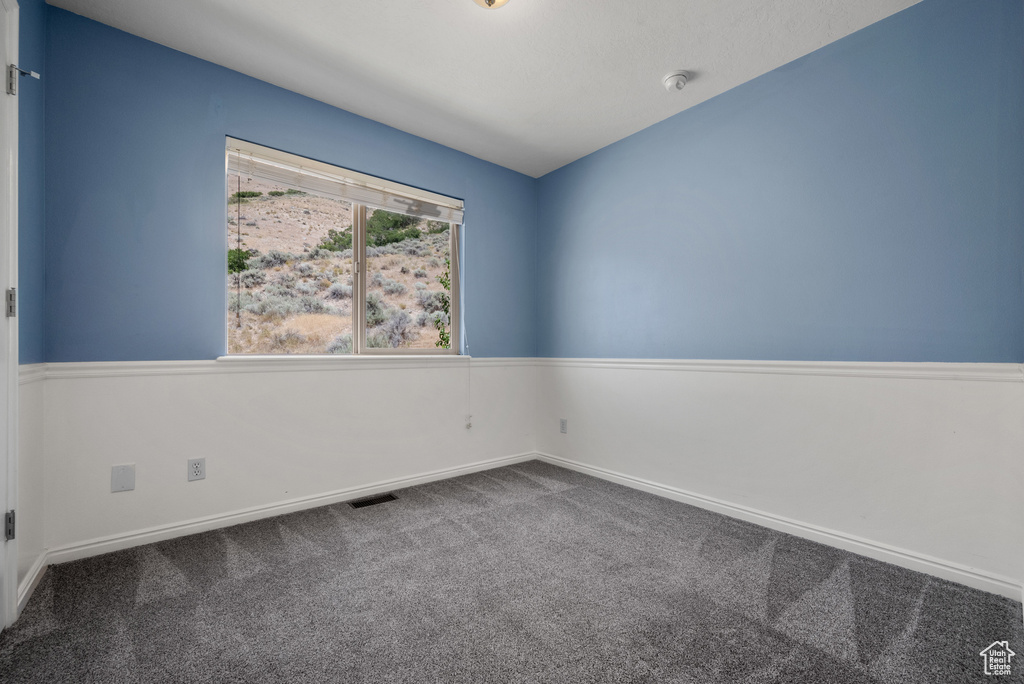 Empty room featuring carpet flooring and a smoke detector