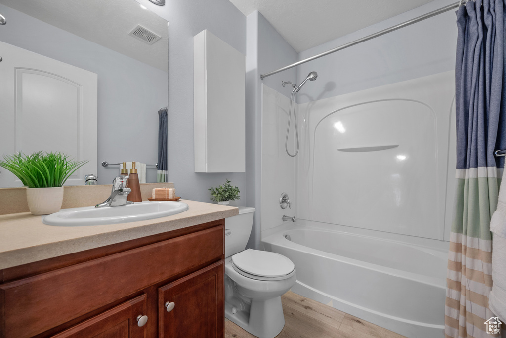 Bathroom with shower / bath combo, vanity, and wood finished floors