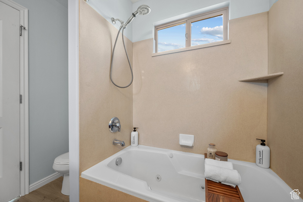 Bathroom with toilet and a combined bath / shower with jetted tub