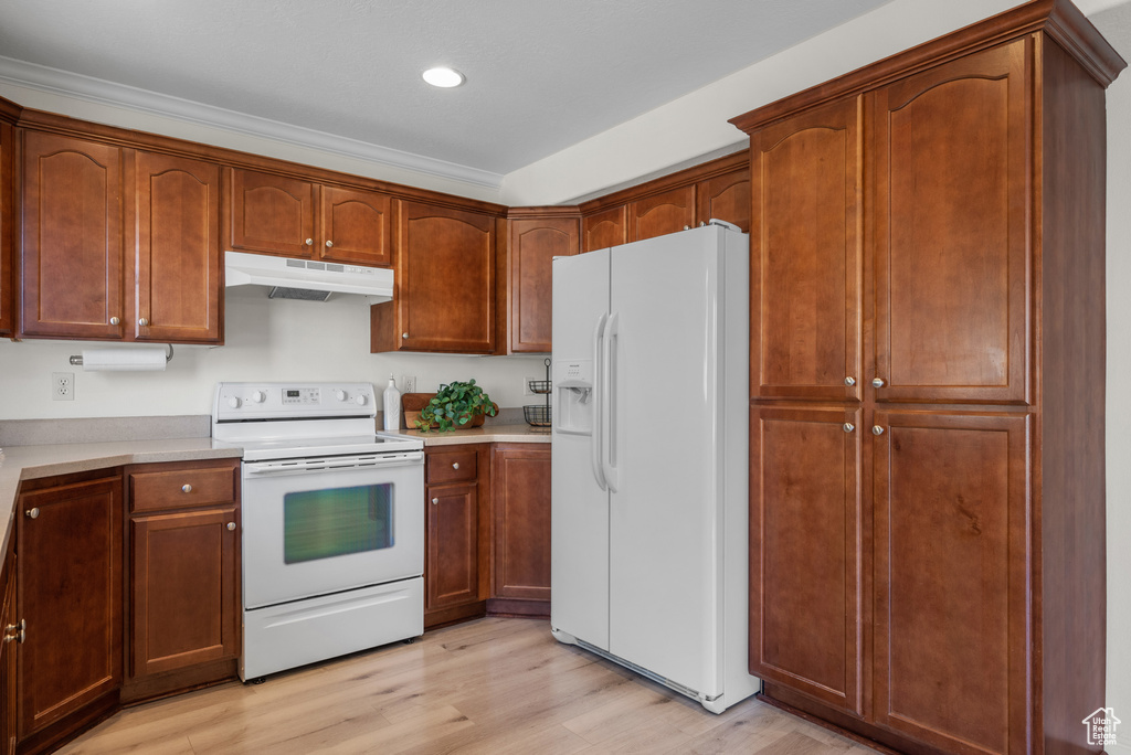 Kitchen with white appliances, under cabinet range hood, light wood finished floors, light countertops, and recessed lighting