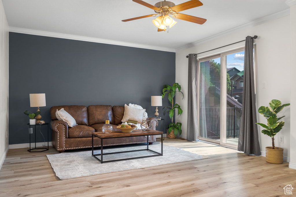Living room with ornamental molding, light wood-type flooring, and ceiling fan
