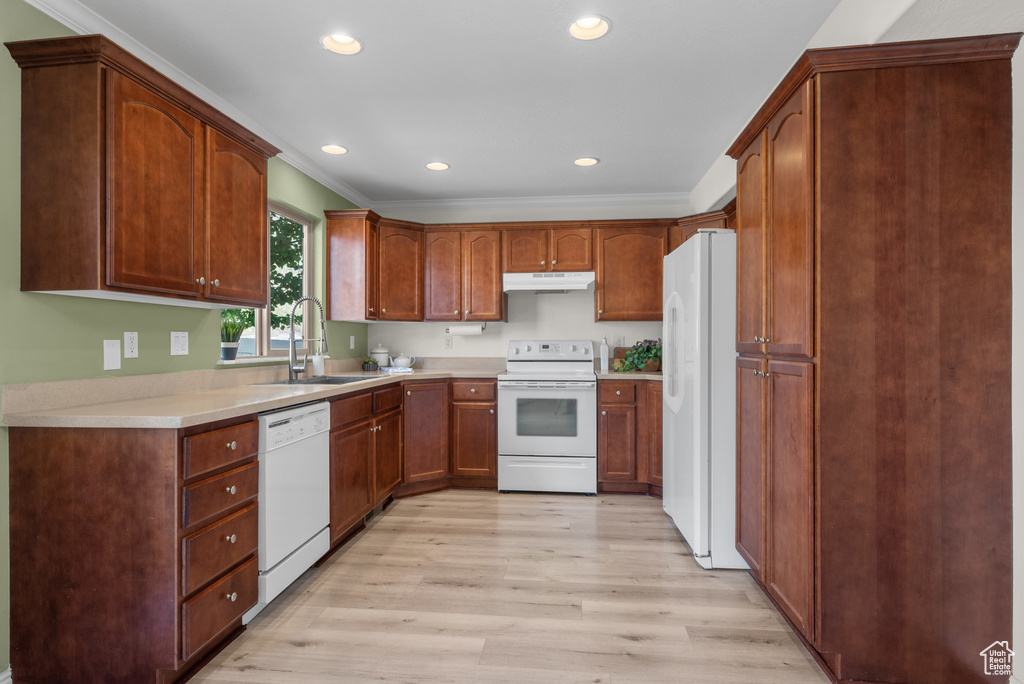 Kitchen featuring white appliances, under cabinet range hood, light wood-type flooring, recessed lighting, and crown molding