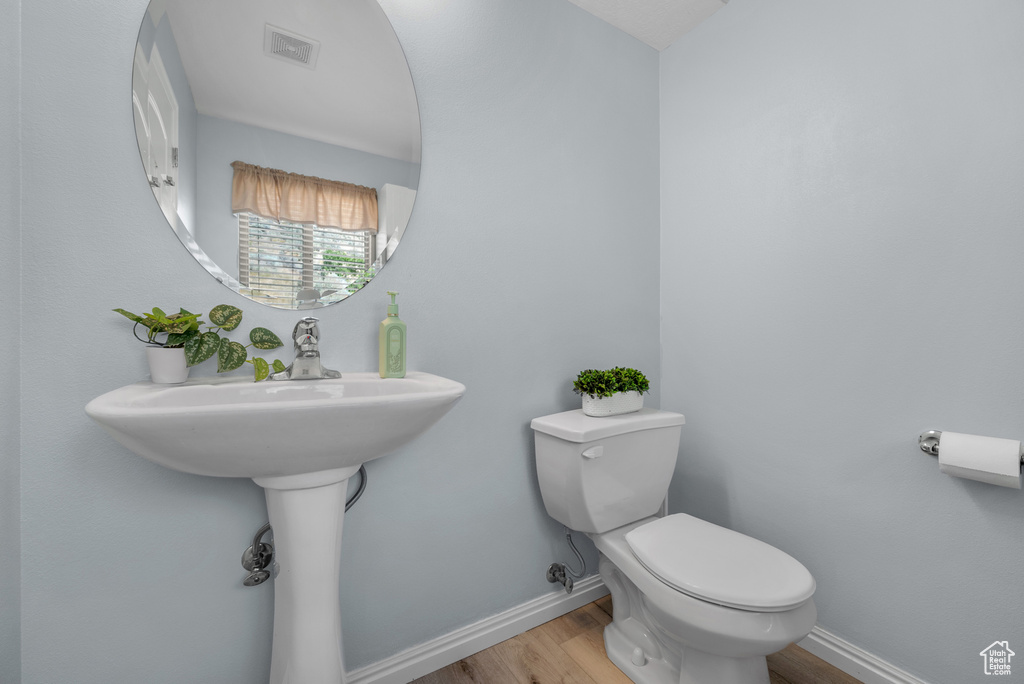 Half bath with wood finished floors and toilet