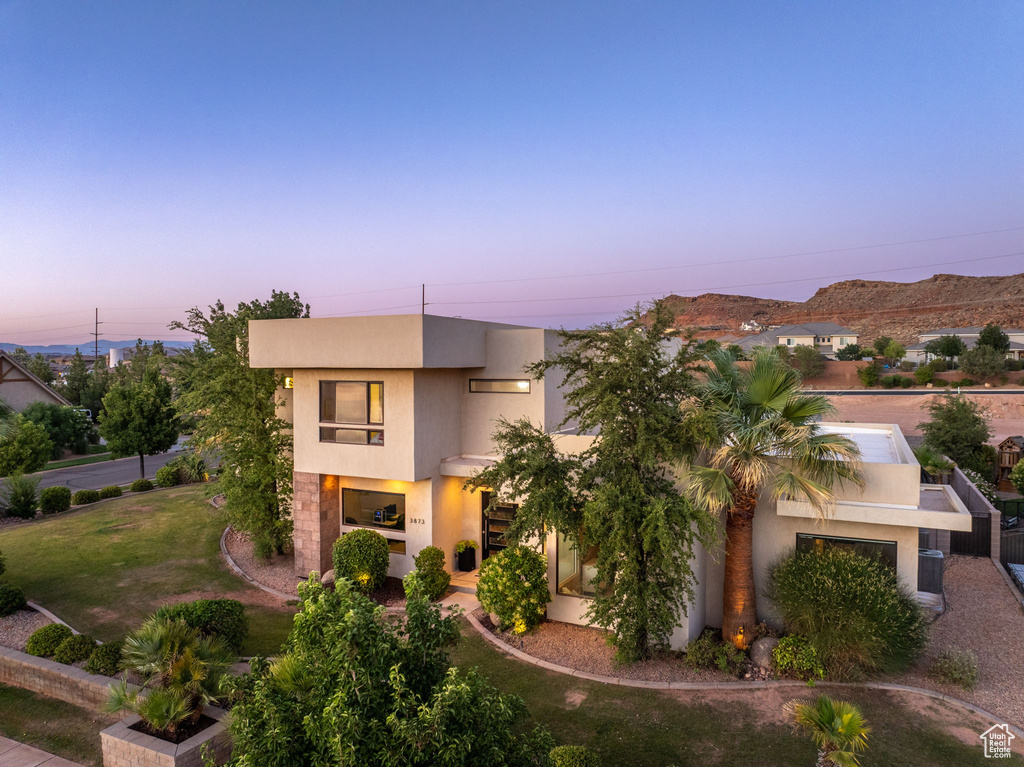 View of front of home with stucco siding and a yard