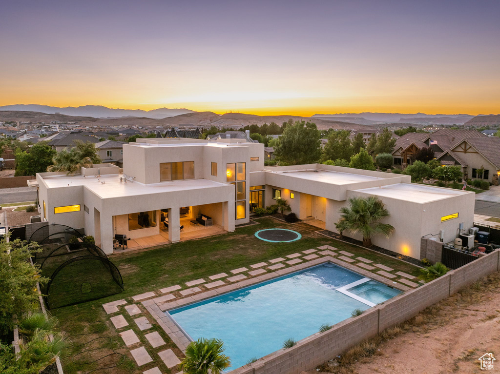 Rear view of house with stucco siding, a patio, a mountain view, a pool with connected hot tub, and a residential view