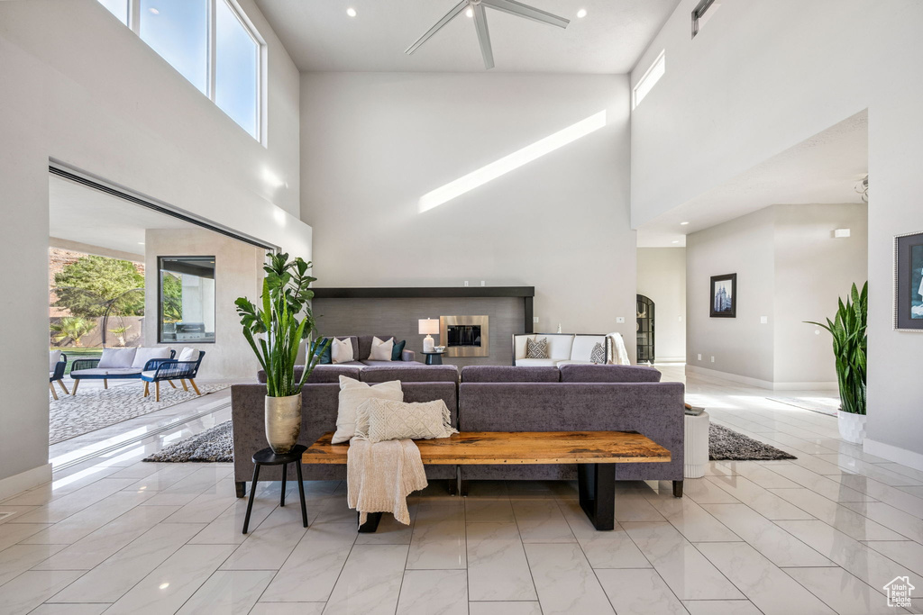 Living area with a towering ceiling, light marble finish floors, and recessed lighting