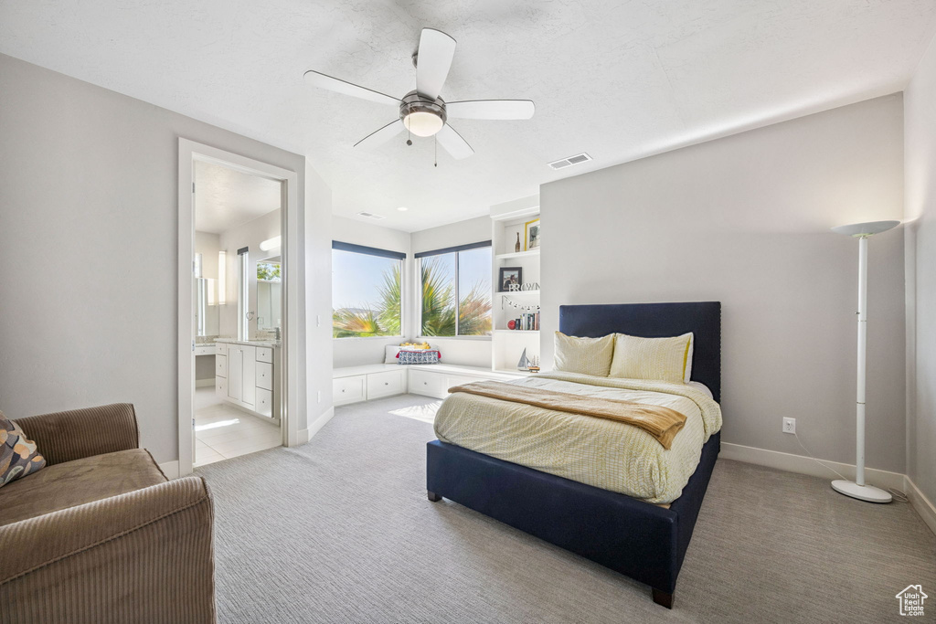 Bedroom with light colored carpet, connected bathroom, and ceiling fan