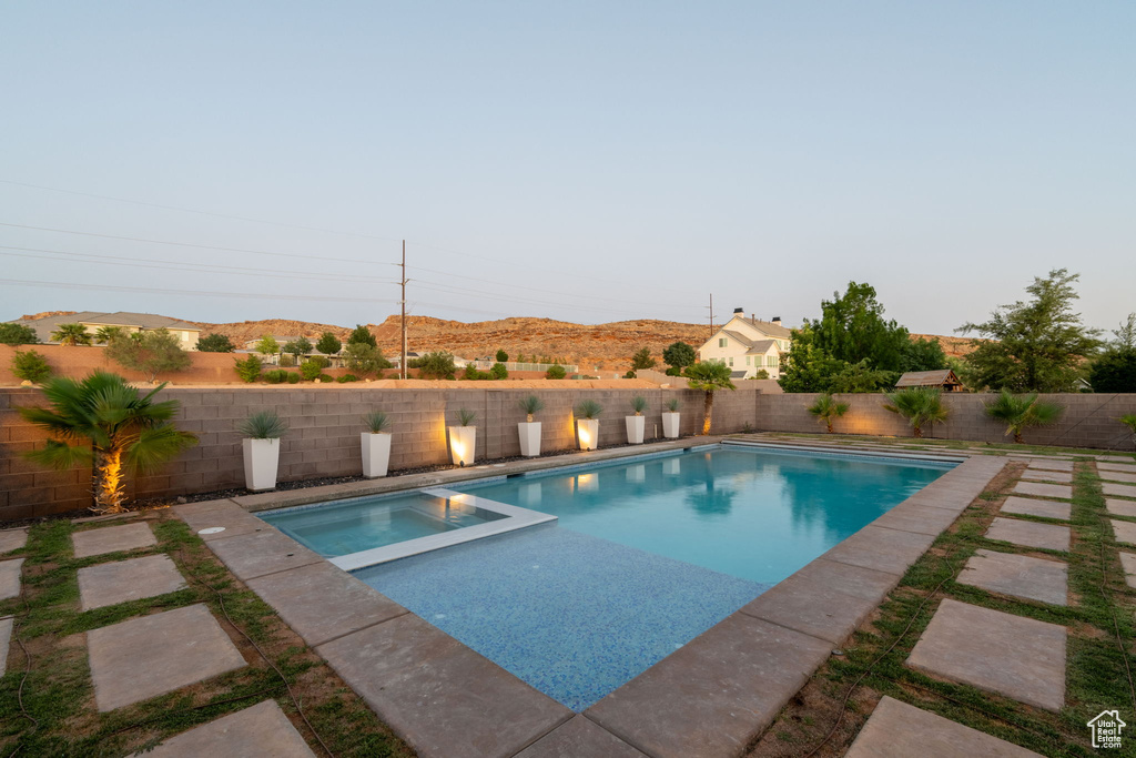 View of swimming pool with a fenced backyard, a pool with connected hot tub, and a mountain view