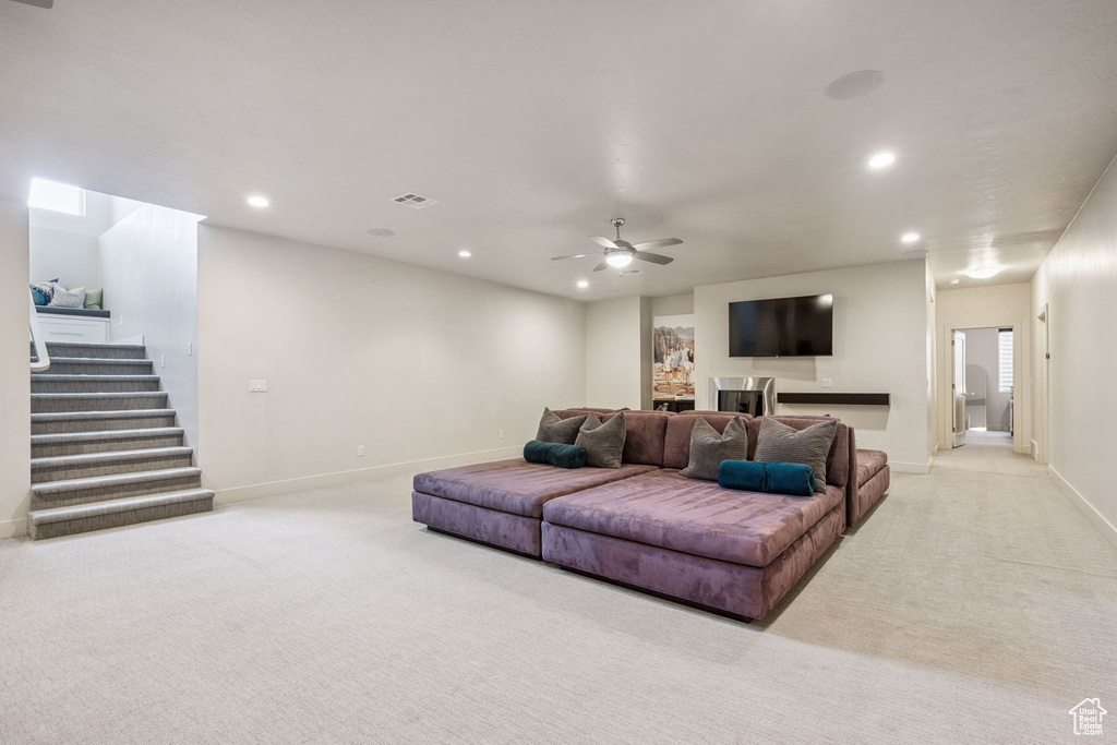 Carpeted living room featuring recessed lighting, stairs, and ceiling fan