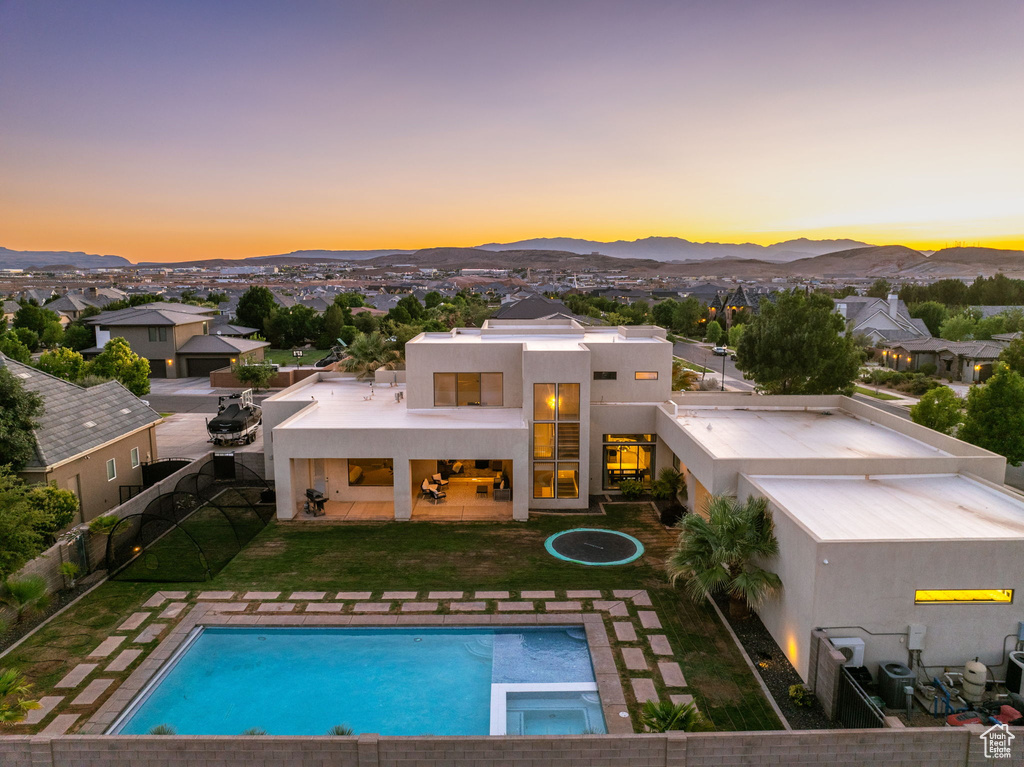 Back of house featuring a mountain view, stucco siding, a patio area, and a pool with connected hot tub