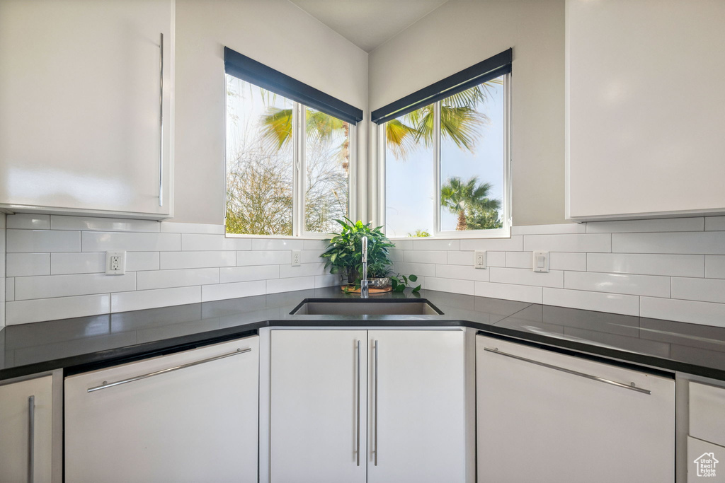 Kitchen with dishwasher, white cabinetry, and dark countertops
