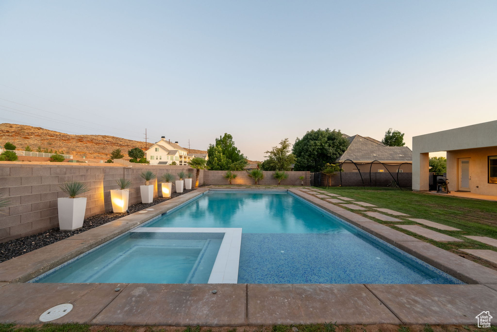 View of swimming pool featuring a fenced backyard and a pool with connected hot tub