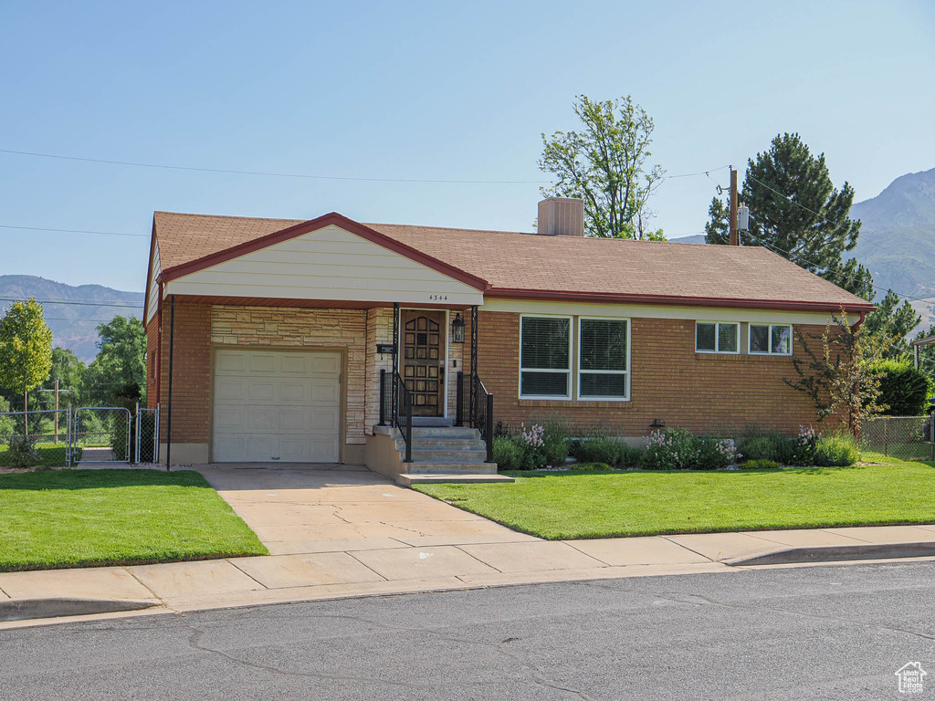 Ranch-style house with an attached garage, a mountain view, a gate, and brick siding