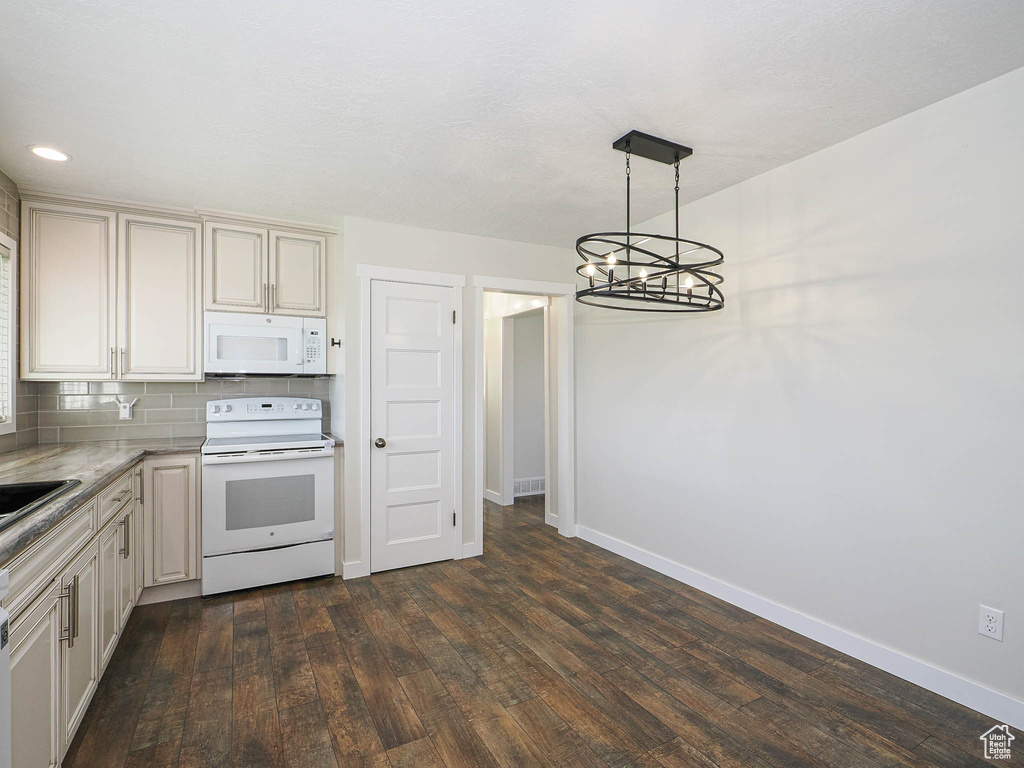 Kitchen with white appliances, dark wood-type flooring, decorative backsplash, a chandelier, and pendant lighting