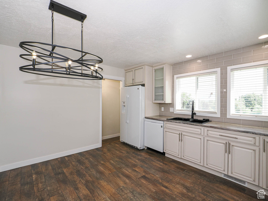 Kitchen featuring white appliances, dark wood-style floors, a chandelier, glass insert cabinets, and a textured ceiling